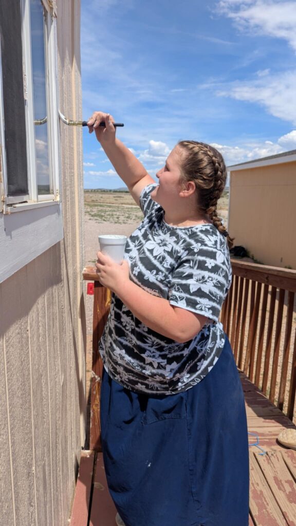 Bonnie paints the trim of a home on the reservation as part of the mission work during the trip to the Navajo Nation.