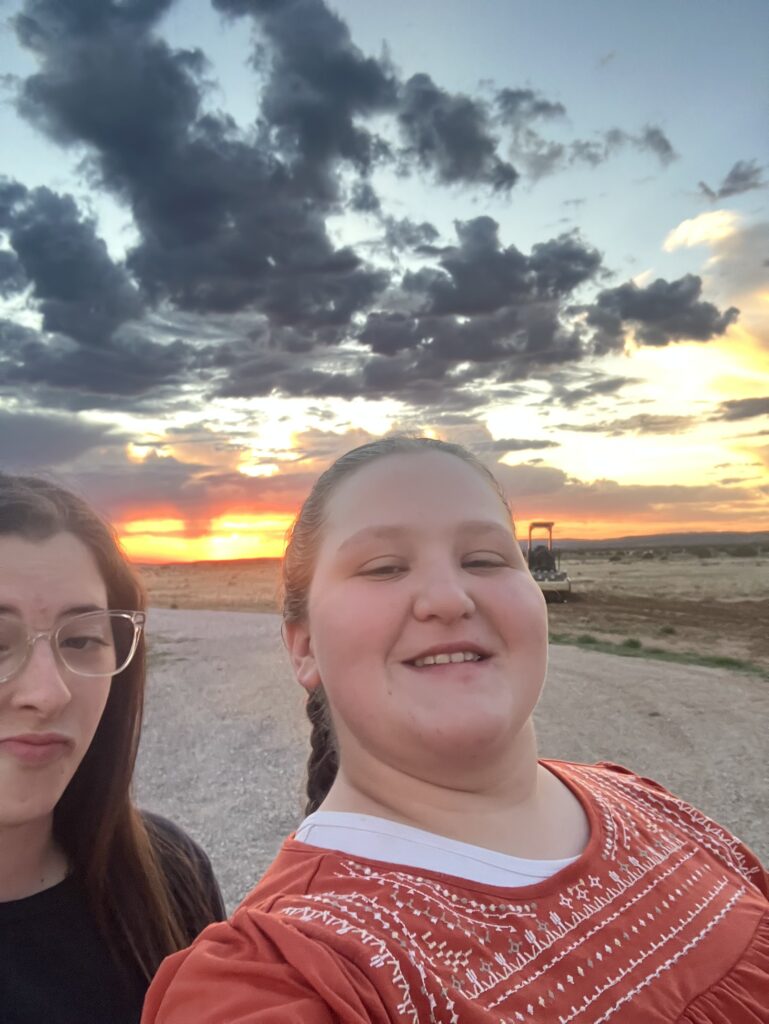 Bonnie and a friend take a selfie during a vibrant desert sunset while serving on the mission trip.