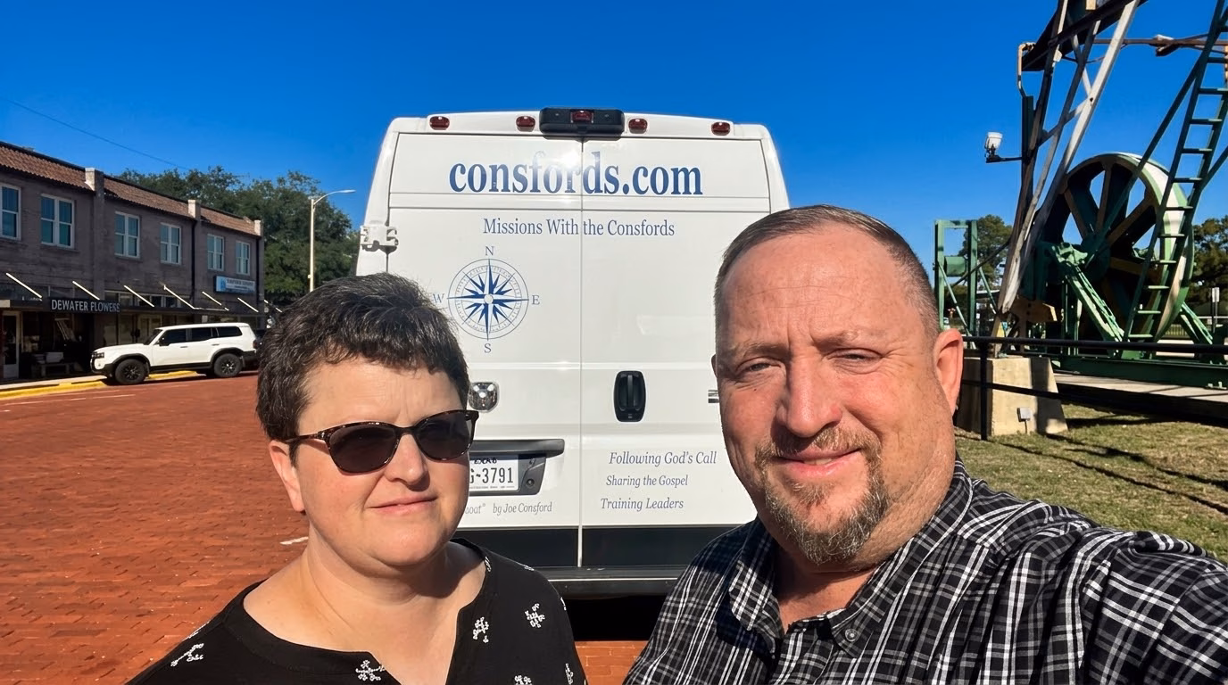 Joe and Laura Consford, Baptist missionaries to Ghana, standing in front of their ministry van lettered consfords.com